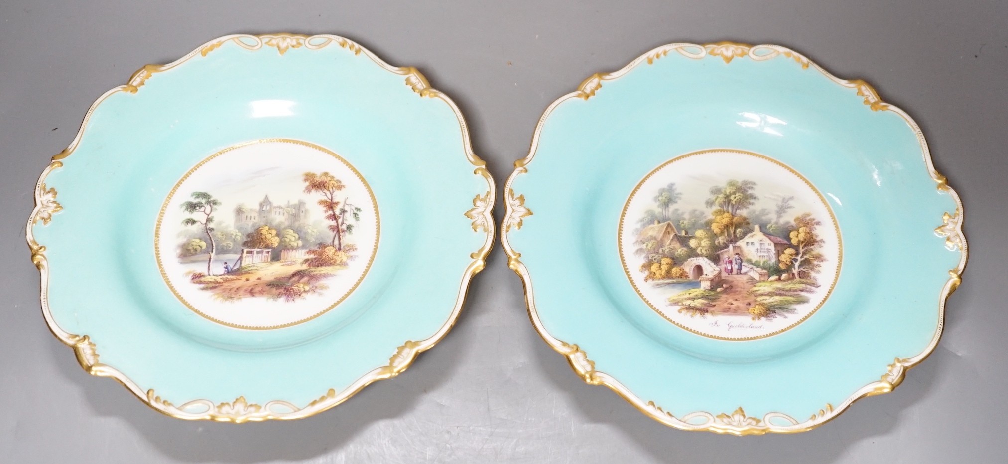 A pair of English porcelain plates with moulded white and turquoise borders both painted with landscapes, one titled in Guildford, diameter 22.5cm